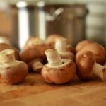 Close-up of fresh brown mushrooms on a wooden cutting board in a kitchen setting.